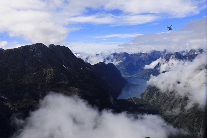 A helicopter flying over snow capped mountains